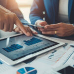 close-up hands of business professionals are analyzing financial charts on a tablet