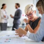 Innovation im Unternehmen: Zwei Kolleginnen prüfen Unternehmenszahlen
