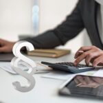 Forschungszulagengesetz: Beratung zum Antrag – Hände am Taschenrechner mit Unterlagen und Laptop